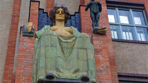 Alegorická postava ženy podpírá bronzovou sochu chlapce, který symbolizuje Salon republiky
