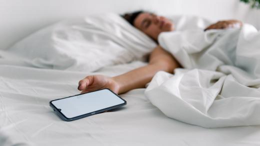 Žena spí v posteli s mobilním telefonem