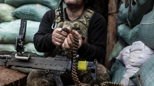 Ukrajinský voják nabíjí kulomet na bojové pozici v zákopu