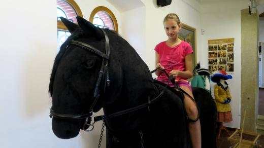 Největší plyšový kůň v Česku pod sedlem návštěvnice Interaktivního muzea starokladrubského koně ve Slatiňanech