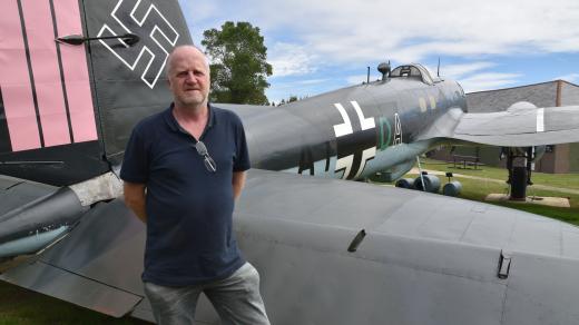 Hrdý průvodce a nadšenec do historie letectví stojí před zrestaurovaným německým bombardérem
