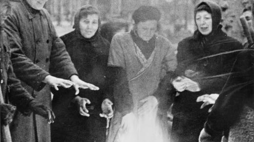Trümmerfrauen se zahřívají u ohně během práce v zimě na přelomu let 1945 a 1946