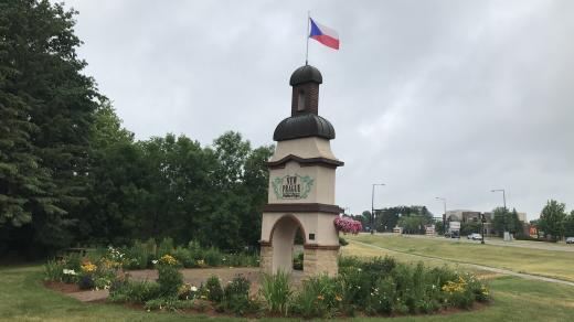 Zdobená brána na východním okraji města, nad kterou se třepetá česká vlajka