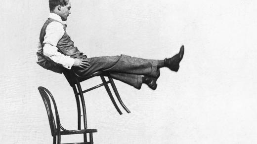 Muž balancující na židlích značky Thonet
