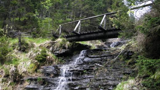 Vodopád překonává most mysliveckého chodníku vedoucího na hřeben