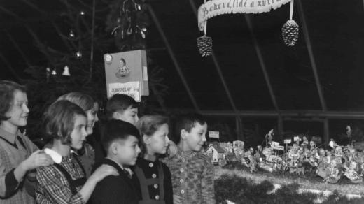 Děti u vánočního stromku, v pozadí kasička na dobrovolné příspěvky (1939)