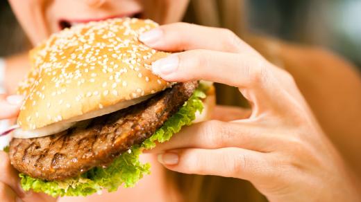 Hamburger, žena jí burger, kouše do hamburgeru