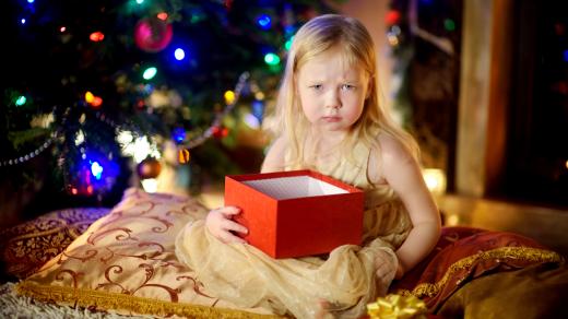 Smutné dítě u vánočního stromečku rozbaluje dárky