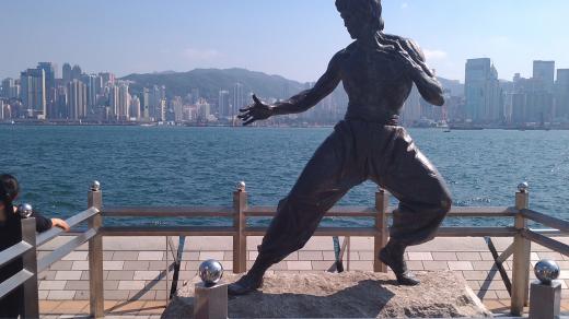 Jedna z raritních fotek bez davů turistů před ikonickou sochou Bruce Leeho na promenádě s výhledem na panorama severní části ostrova Hongkong