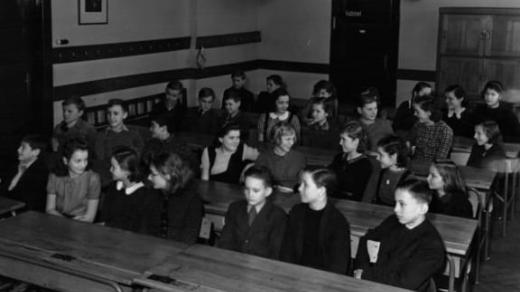 Žáci pokusné měšťanské školy v Nuslích čekají na vánoční nadílku Národního souručenství (20. 12. 1939)