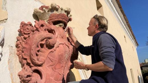 Restaurátor Ivan Sámel obnovuje kamenný erb na barokní sýpce ve Strakonicích
