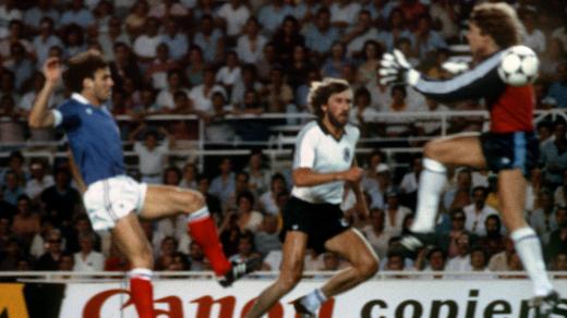 Harald Schumacher (vpravo) těsně před tím, než brutálně zfauloval francouzského hráče Patricka Battistona (vlevo) na mistrovství světa v roce 1982. Fanoušci si ale možná pamatují i domluvený zápas Němců s Rakouskem