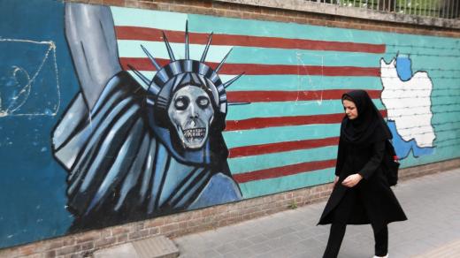 Íránka kráčí podél výmluvné nástěnné malby na zdi, která obklopuje areál bývalé americké ambasády v Teheránu (8. května 2018). 