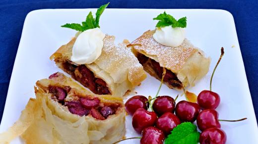 Třešňový štrůdl ozdobte zakysanou smetanou, šlehačkou nebo vanilkovým pudinkem a přidejte lístky máty